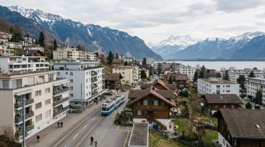 Vue panoramique sur une ville suisse avec immeubles résidentiels et montagnes, illustrant le marché immobilier suisse